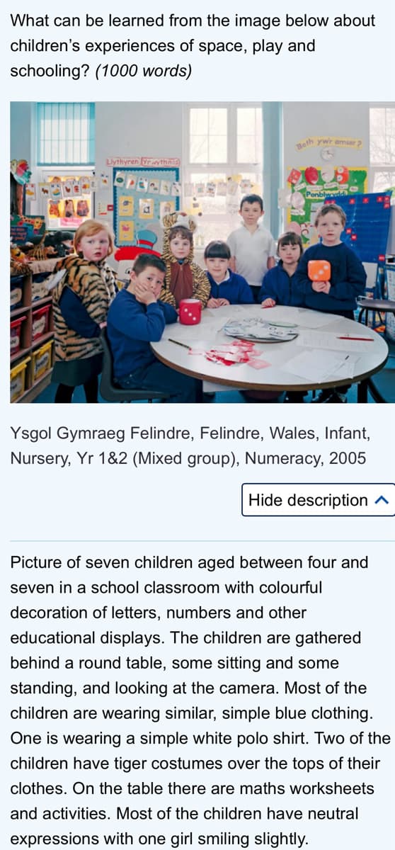 What can be learned from the image below about
children's experiences of space, play and
schooling? (1000 words)
Beth ywr amser ?
Ysgol Gymraeg Felindre, Felindre, Wales, Infant,
Nursery, Yr 1&2 (Mixed group), Numeracy, 2005
Hide description A
Picture of seven children aged between four and
seven in a school classroom with colourful
decoration of letters, numbers and other
educational displays. The children are gathered
behind a round table, some sitting and some
standing, and looking at the camera. Most of the
children are wearing similar, simple blue clothing.
One is wearing a simple white polo shirt. Two of the
children have tiger costumes over the tops of their
clothes. On the table there are maths worksheets
and activities. Most of the children have neutral
expressions with one girl smiling slightly.