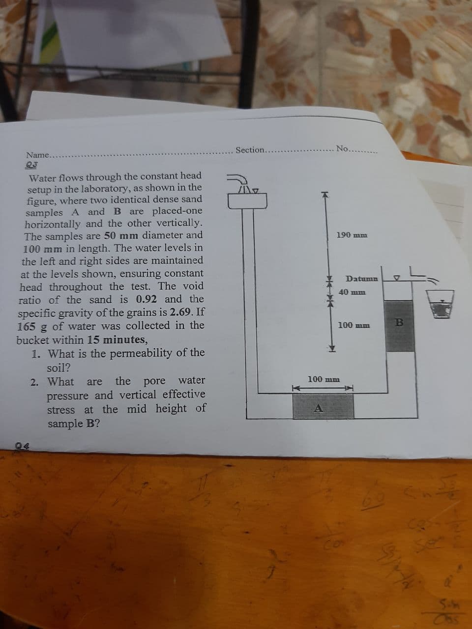 Section.
No...
Name..
23
Water flows through the constant head
setup in the laboratory, as shown in the
figure, where two identical dense sand
samples A and B
horizontally and the other vertically.
The samples are 50 mm diameter and
100 mm in length. The water levels in
the left and right sides are maintained
at the levels shown, ensuring constant
head throughout the test. The void
ratio of the sand is 0.92 and the
are placed-one
190 mm
Datumn
40 mm
specific gravity of the grains is 2.69. If
165
of water was collected in the
100 mm
B
bucket within 15 minutes,
1. What is the permeability of the
soil?
100 mm
2. What
the pore
water
are
pressure and vertical effective
stress at the mid height of
sample B?
04
