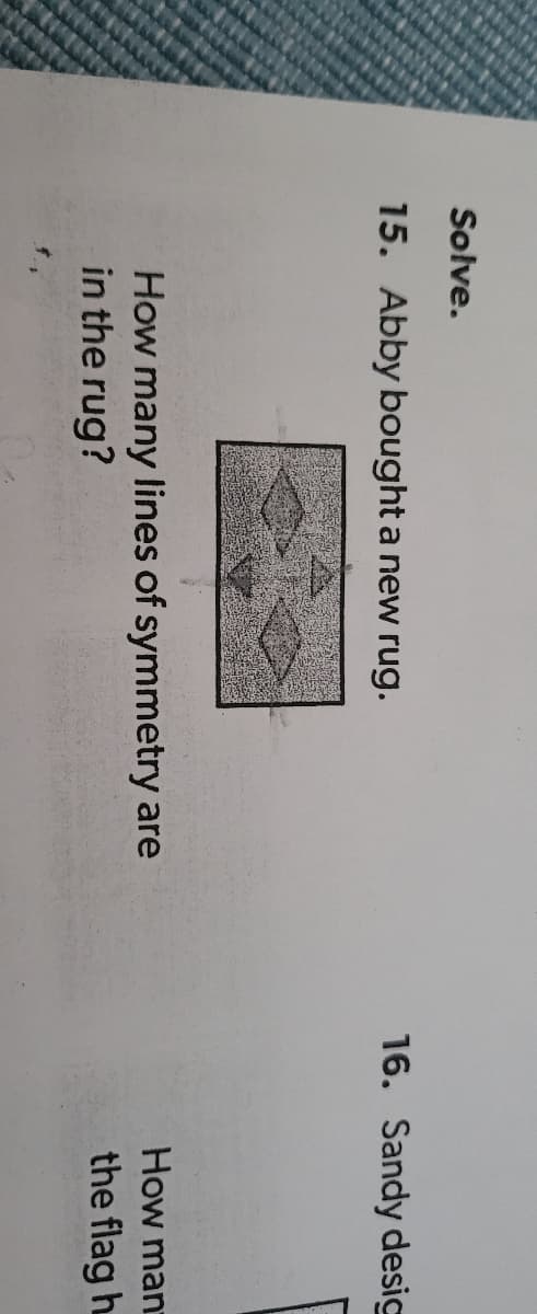 Solve.
15. Abby bought a new rug.
16. Sandy desig
How man
How many lines of symmetry are
in the rug?
the flag h
